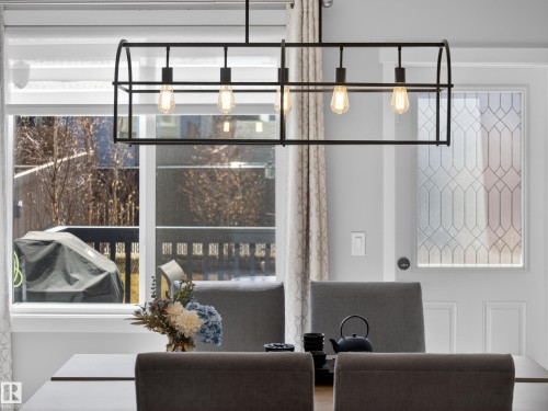 Contemporary linear chandelier with Edison-style bulbs illuminating a dining space - 323 Balsam Link, Leduc, AB - Indoor Photo Showing Other Room