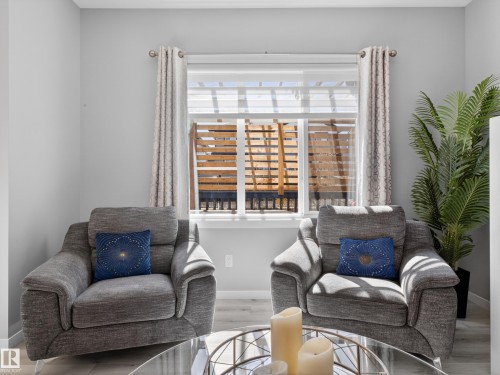 Bright interior space featuring a window with roller shades, light-toned walls, and wood-finish flooring - 323 Balsam Link, Leduc, AB - Indoor Photo Showing Living Room