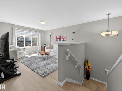 Bright living area featuring wood-finish flooring, a large window with blinds, and neutral wall tones - 323 Balsam Link, Leduc, AB - Indoor