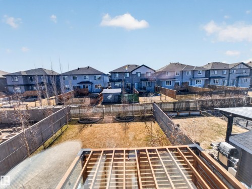 Expansive backyard featuring a partial deck frame with glass railing, a paved patio area, and perimeter fencing - 323 Balsam Link, Leduc, AB - Outdoor