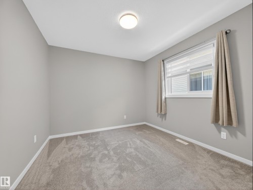 Neutral-toned interior with light gray walls, textured carpeting, and white baseboards - 323 Balsam Link, Leduc, AB - Indoor Photo Showing Other Room