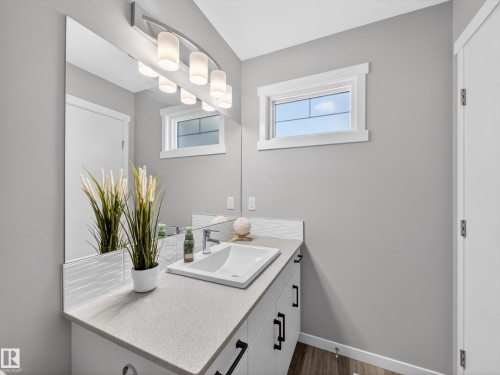 Bathroom vanity featuring a rectangular undermount sink, a light speckled countertop, and a white wave-patterned tile backsplash - 323 Balsam Link, Leduc, AB - Indoor Photo Showing Bathroom