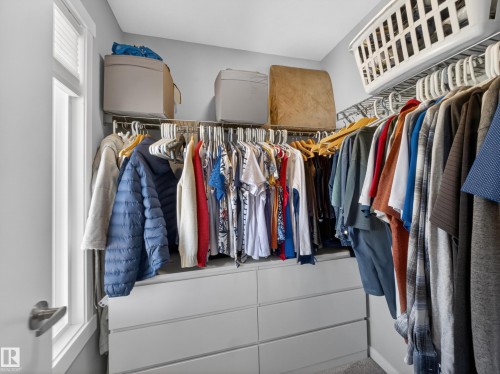Integrated closet organization system featuring white drawers, upper shelving, and ample hanging space - 323 Balsam Link, Leduc, AB - Indoor With Storage