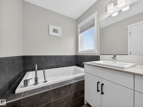 Built-in soaker tub featuring chrome fixtures and dark tile surround - 323 Balsam Link, Leduc, AB - Indoor Photo Showing Bathroom