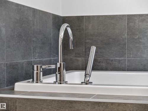 Bathtub featuring chrome deck-mounted faucet with lever controls and a hand shower - 323 Balsam Link, Leduc, AB - Indoor Photo Showing Bathroom