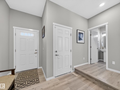 Entryway featuring light wood-finish flooring, light grey walls, white trim, and a panel door with transom window - 323 Balsam Link, Leduc, AB - Indoor Photo Showing Other Room