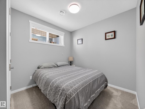 Carpeted bedroom featuring light gray walls, a horizontal window with white trim, and a flush-mount ceiling light fixture - 323 Balsam Link, Leduc, AB - Indoor Photo Showing Bedroom