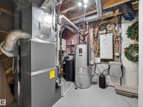 Utility area featuring a water heater, water softener, electrical panel, and HVAC system with exposed ductwork - 323 Balsam Link, Leduc, AB - Indoor Photo Showing Basement
