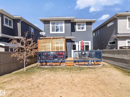 Rear exterior featuring a two-tiered wooden deck with blue railings, horizontal slatted wood privacy screen, and a ground-level patio space - 323 Balsam Link, Leduc, AB - Outdoor With Deck Patio Veranda With Exterior