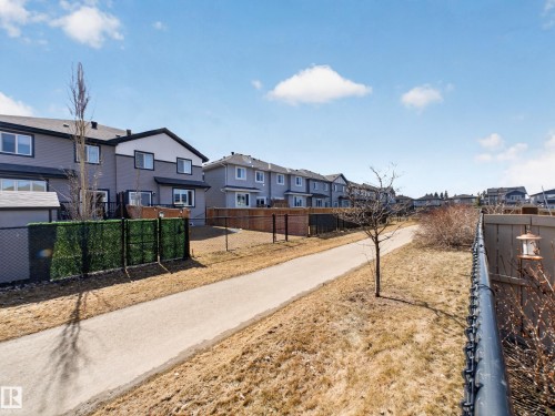 Paved pathway bordering the property, featuring a black chain-link fence and a decorative privacy screen - 323 Balsam Link, Leduc, AB - Outdoor