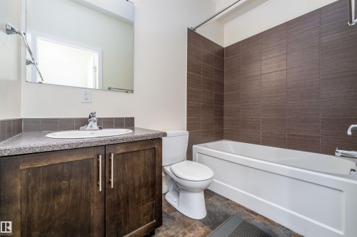 Full bathroom featuring bathtub / shower combination, vanity, and dark stone finish flooring - 12246 103 Street Nw, Edmonton, AB - Indoor Photo Showing Bathroom