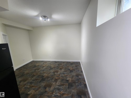 Below grade area featuring stone finish floors and freestanding refrigerator - 12246 103 Street Nw, Edmonton, AB - Indoor Photo Showing Other Room