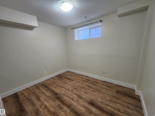 Below grade area featuring a textured ceiling and dark wood-style flooring - 12246 103 Street Nw, Edmonton, AB - Indoor Photo Showing Other Room