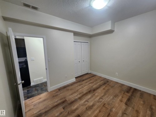 Unfurnished bedroom with a textured ceiling, wood finished floors, and a closet - 12246 103 Street Nw, Edmonton, AB - Indoor Photo Showing Other Room