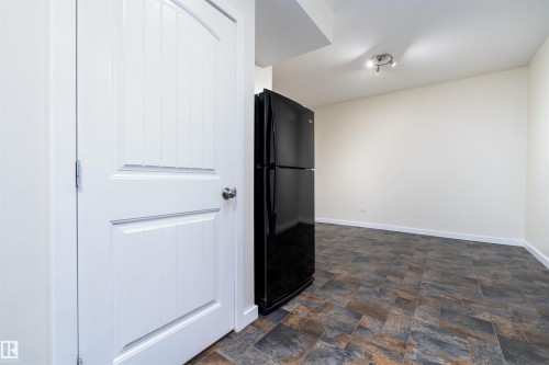 Unfurnished bedroom with freestanding refrigerator and stone finish floors - 12246 103 Street Nw, Edmonton, AB - Indoor Photo Showing Other Room