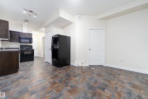 Kitchen with dark brown cabinetry, black appliances, light countertops, and stone finish floors - 12246 103 Street Nw, Edmonton, AB - Indoor Photo Showing Kitchen