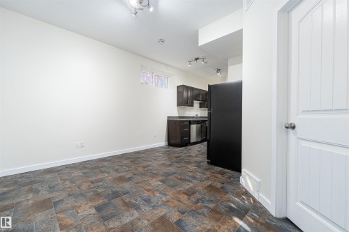 Kitchen featuring dark brown cabinetry, freestanding refrigerator, stone finish floors, track lighting, and dishwasher - 12246 103 Street Nw, Edmonton, AB - Indoor