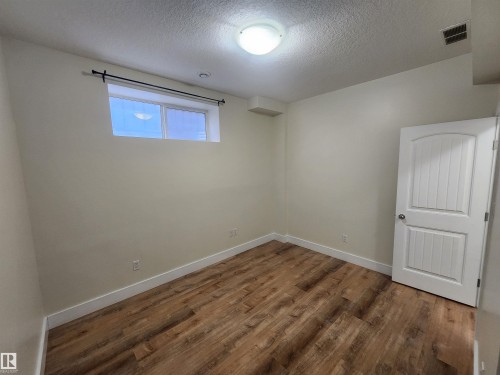 Empty room with a textured ceiling and dark wood-type flooring - 12246 103 Street Nw, Edmonton, AB - Indoor Photo Showing Other Room