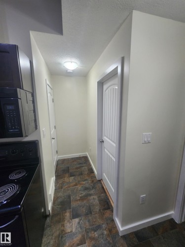 Hall featuring a textured ceiling and stone finish flooring - 12246 103 Street Nw, Edmonton, AB - Indoor Photo Showing Other Room