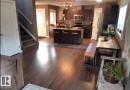Kitchen at the main floor featuring a breakfast bar area, stainless steel appliances, dark wood-style flooring, a center island with sink, and a chandelier - 12246 103 Street Nw, Edmonton, AB  - Indoor Photo Showing Other Room 