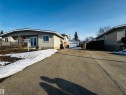The property features a front porch with a lattice privacy screen, double entry doors, and a paved driveway leading to a detached garage - 11452 152B Avenue, Edmonton, AB  - Outdoor 