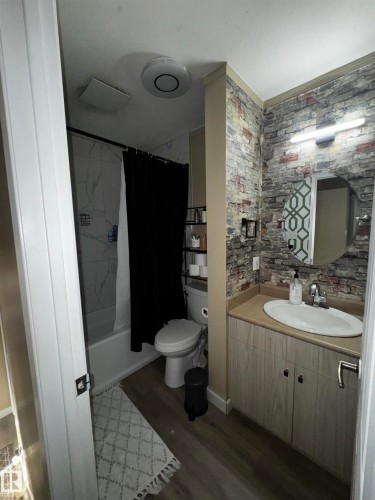 The bathroom features a vanity with a light wood-grain cabinet, a beige countertop, and a white oval sink - 11452 152B Avenue, Edmonton, AB - Indoor Photo Showing Bathroom