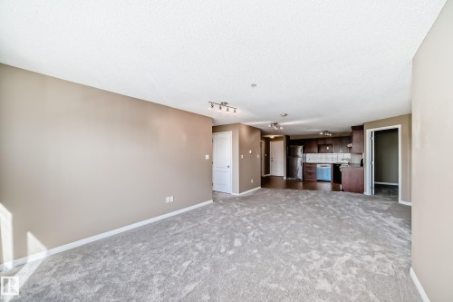 Spacious main living area featuring neutral-toned carpeting, track lighting, and a neutral wall palette - 344 1520 Hammond Gate Gate, Edmonton, AB - Indoor Photo Showing Other Room