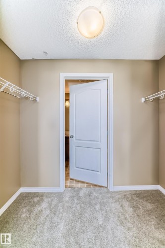 Spacious walk-in closet featuring light-colored carpeting, neutral painted walls, and built-in wire shelving systems - 344 1520 Hammond Gate Gate, Edmonton, AB - Indoor Photo Showing Other Room