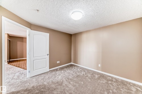 Spacious room featuring neutral-toned walls, textured ceiling, and plush gray carpeting - 344 1520 Hammond Gate Gate, Edmonton, AB - Indoor Photo Showing Other Room
