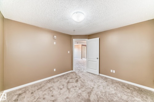 Carpeted room featuring neutral wall tones, white baseboards, and a semi-flush mount ceiling light fixture - 344 1520 Hammond Gate Gate, Edmonton, AB - Indoor Photo Showing Other Room