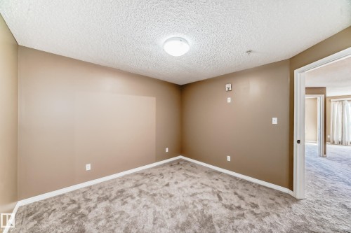 Carpeted interior room with neutral-toned walls, white baseboards, and a textured ceiling - 344 1520 Hammond Gate Gate, Edmonton, AB - Indoor Photo Showing Other Room