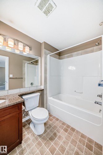 Full bathroom featuring a tub/shower combination, a vanity with a granite-style countertop, and tile flooring - 344 1520 Hammond Gate Gate, Edmonton, AB - Indoor Photo Showing Bathroom