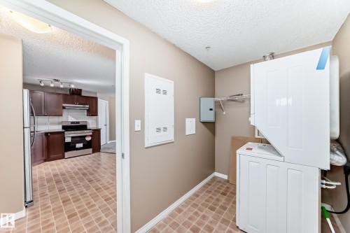 Laundry area featuring a stackable washer and dryer, neutral wall paint, and durable tile-patterned flooring - 344 1520 Hammond Gate Gate, Edmonton, AB - Indoor Photo Showing Laundry Room