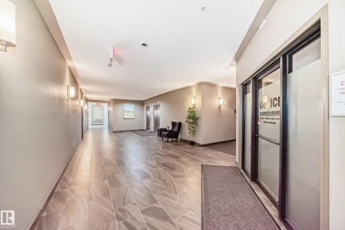 Spacious common area featuring large format tile flooring, wall-mounted sconces, and two elevators with stainless steel finishes - 344 1520 Hammond Gate Gate, Edmonton, AB - Indoor Photo Showing Other Room