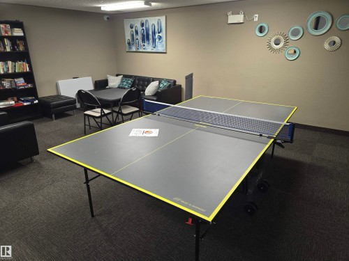 Recreational room featuring a ping pong table, modular seating with a sofa and armchairs, a built-in bookshelf, and wall-mounted art - 344 1520 Hammond Gate Gate, Edmonton, AB - Indoor Photo Showing Other Room
