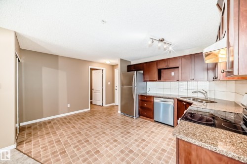 Efficient kitchen with wood cabinetry, stainless steel appliances, granite countertops, and a tile backsplash - 344 1520 Hammond Gate Gate, Edmonton, AB - Indoor Photo Showing Kitchen With Double Sink