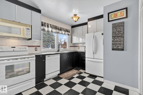 Kitchen featuring black and white checkerboard flooring, white subway tile backsplash, white appliances, and a built-in microwave - 9112 130 Avenue, Edmonton, AB - Indoor Photo Showing Kitchen