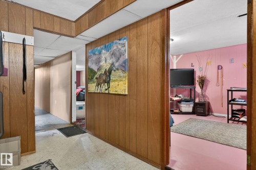 Wood-paneled wall with an open doorway leading to a room featuring pink walls and flooring - 9112 130 Avenue, Edmonton, AB - Indoor Photo Showing Other Room