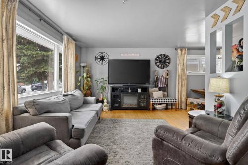 Spacious living area featuring large windows, wood-finish flooring, recessed wall niches, and a built-in media console with an electric fireplace - 9112 130 Avenue, Edmonton, AB - Indoor Photo Showing Living Room