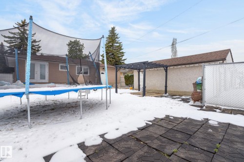 Expansive rear yard featuring a paved patio area, a pergola structure, and a chain-link fence - 9112 130 Avenue, Edmonton, AB - Outdoor