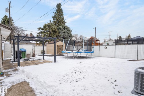 Expansive backyard featuring a pergola-covered patio with concrete pavers, a chain-link fence, and a utility shed - 9112 130 Avenue, Edmonton, AB - Outdoor