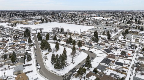 Residential area featuring a mix of single-story and multi-story homes, snow-covered roofs, and mature evergreen trees - 9112 130 Avenue, Edmonton, AB - Outdoor With View