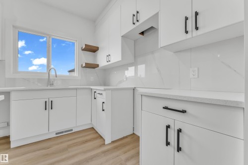 Modern kitchen with white cabinetry and dark hardware, featuring light-colored countertops and a matching backsplash - 277 Munn Way, Leduc, AB - Indoor Photo Showing Kitchen