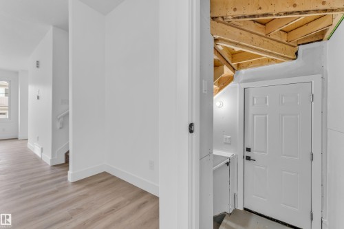 Partially finished lower level featuring exposed wood joists and a paneled entry door with black hardware - 277 Munn Way, Leduc, AB - Indoor Photo Showing Other Room