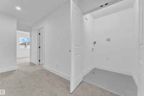 Dedicated laundry area with utility hookups and a finished floor, featuring a bright white color palette and recessed lighting - 277 Munn Way, Leduc, AB - Indoor Photo Showing Other Room