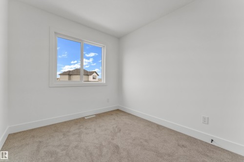 Bright interior space featuring a double-pane window, neutral carpet flooring, and white baseboards - 277 Munn Way, Leduc, AB - Indoor Photo Showing Other Room