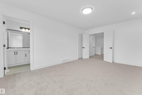 Spacious room featuring light-colored carpeting, white walls, and a contemporary ceiling light fixture - 277 Munn Way, Leduc, AB - Indoor Photo Showing Other Room
