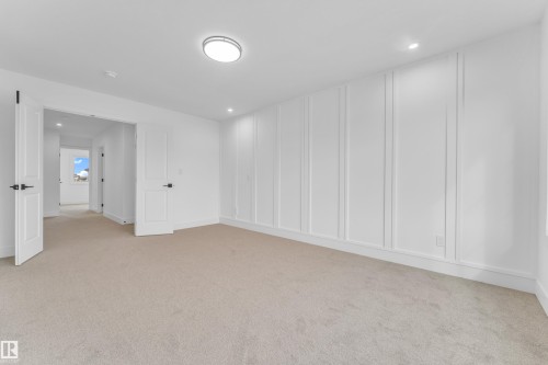 Spacious room featuring neutral carpeting, white paneled accent wall, recessed lighting, and a modern flush-mount ceiling fixture - 277 Munn Way, Leduc, AB - Indoor Photo Showing Other Room