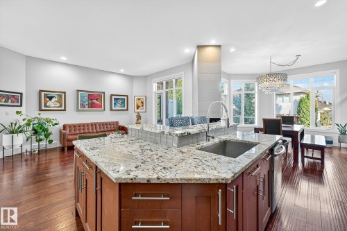 Kitchen with light stone counters, recessed lighting, an island with sink, dark wood-style floors, and a chandelier - 940 Haliburton Road, Edmonton, AB - Indoor Photo Showing Kitchen