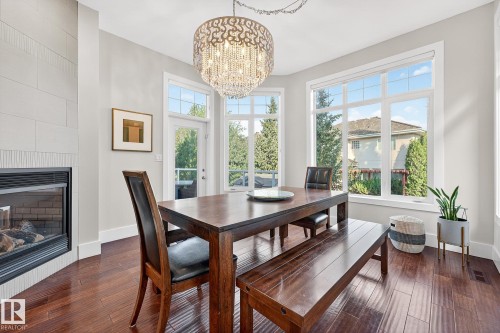 Dining room with dark wood-style flooring, a chandelier, and a fireplace - 940 Haliburton Road, Edmonton, AB - Indoor Photo Showing Dining Room With Fireplace